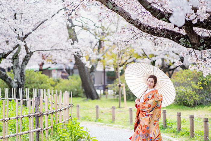 桜の木の下で傘を持って